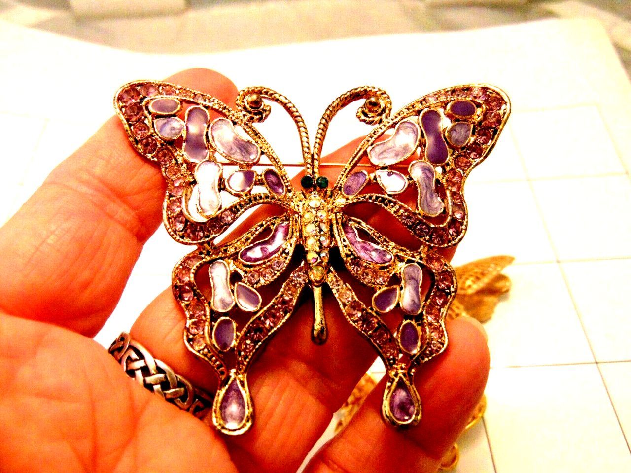 Three brooches in the shape of butterflies are on a checkered surface