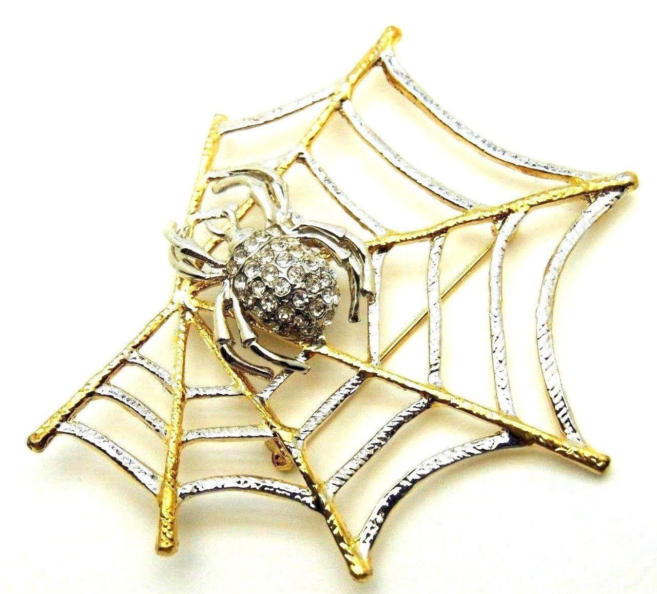 A person is holding a brooch in the shape of a spider web.