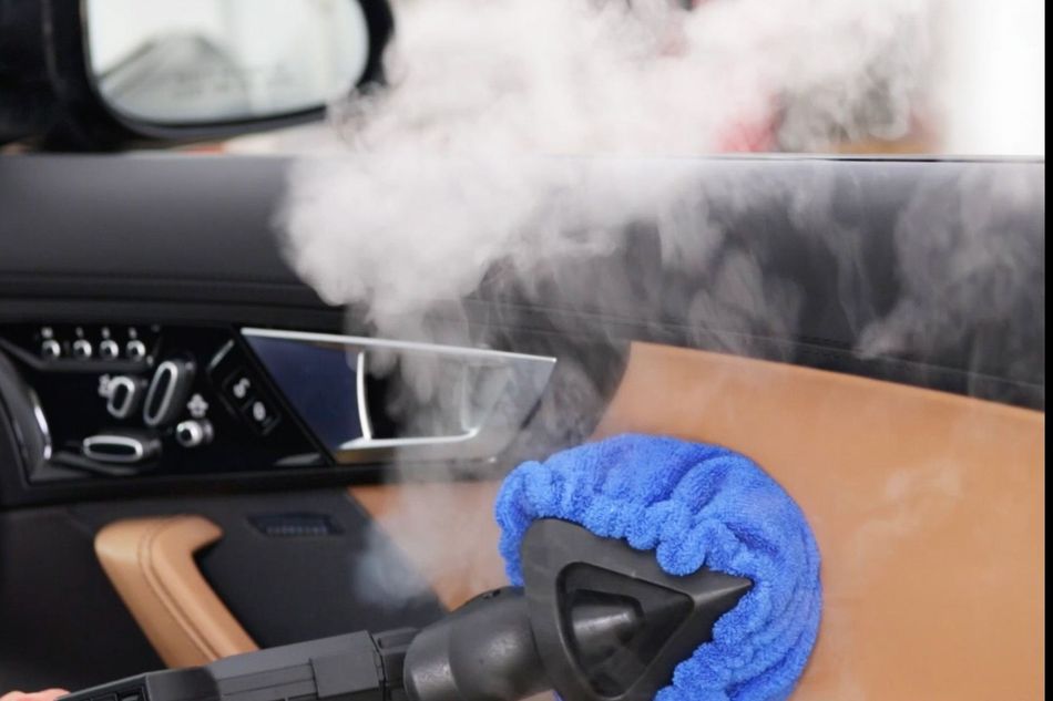A person is polishing the fender of a car with a sander.