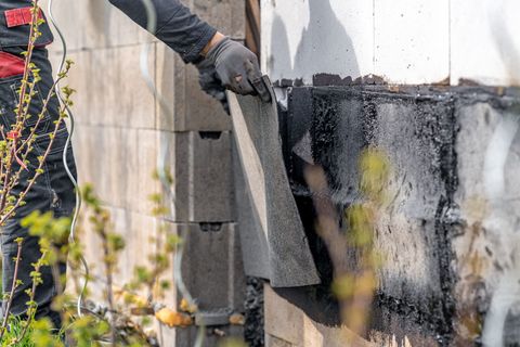 a man in black work clothes and gloves cleaning a building