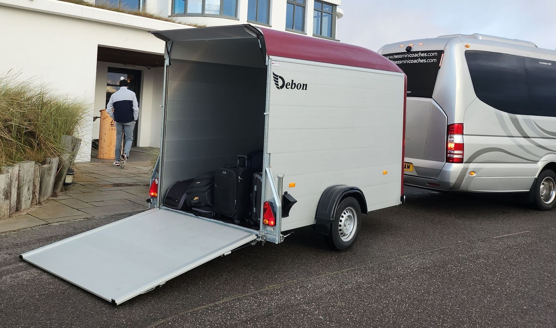 A trailer with the door open is being towed by a van