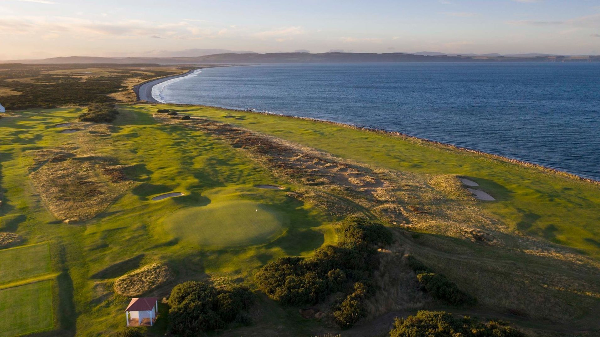 An aerial view of a golf course next to the ocean.