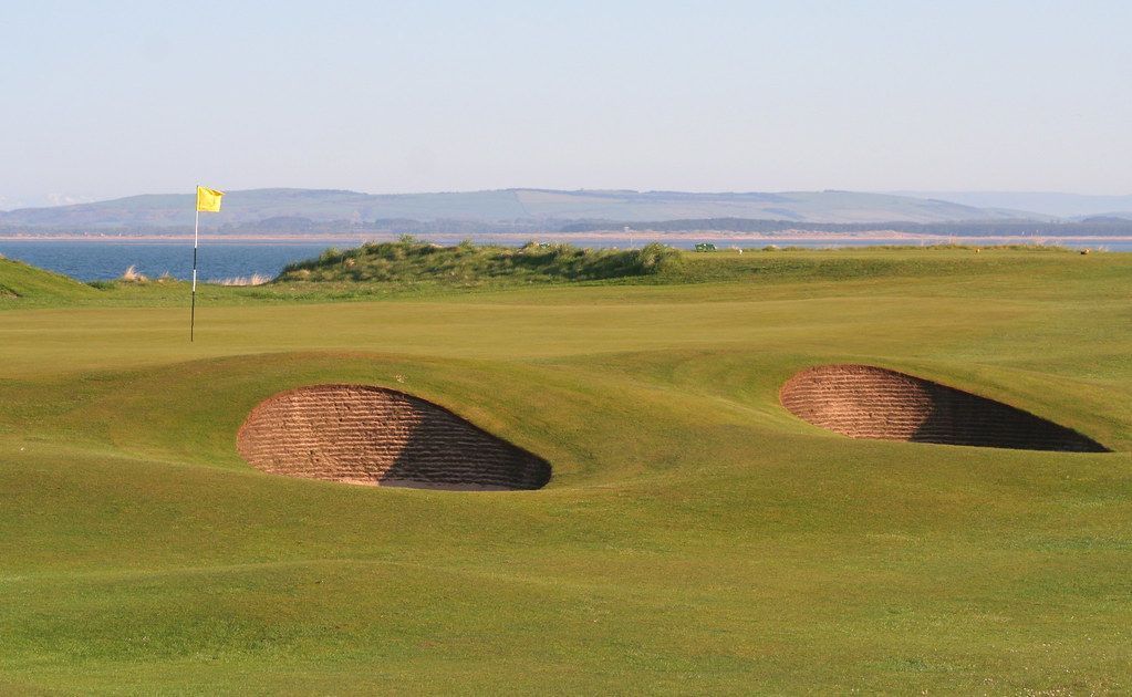 A golf course with two sand bunkers on the green.