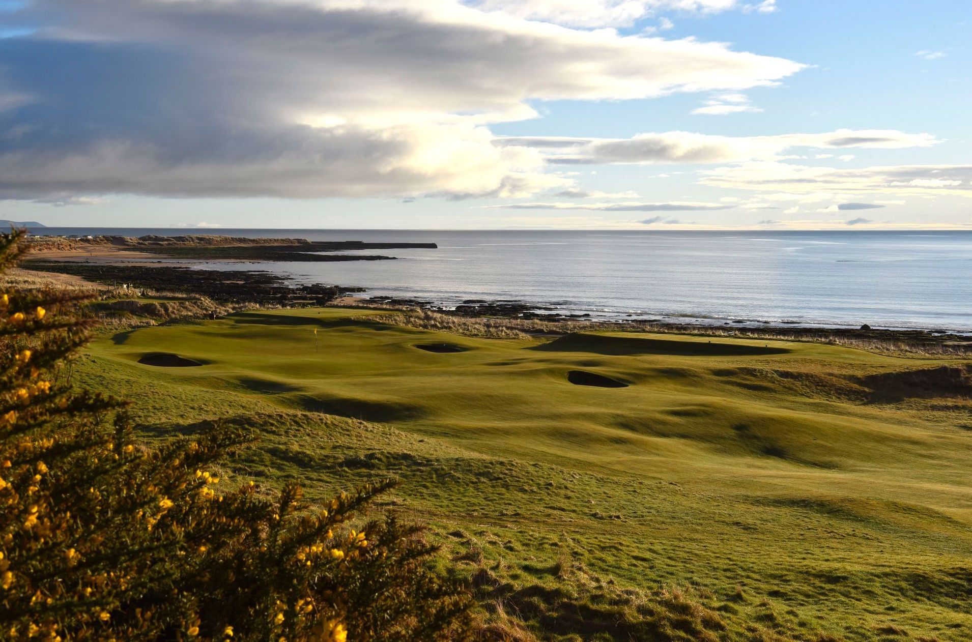 A view of a golf course with a body of water in the background.