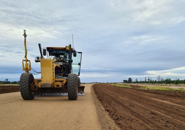 A yellow bulldozer is driving down a dirt road.