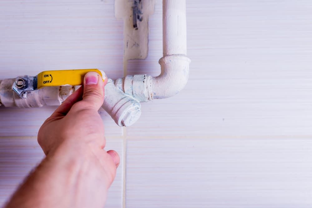 A Person is Fixing a Pipe With a Yellow Valve — Mainline Plumbing & Civil Pty Ltd In Balmain, NSW
