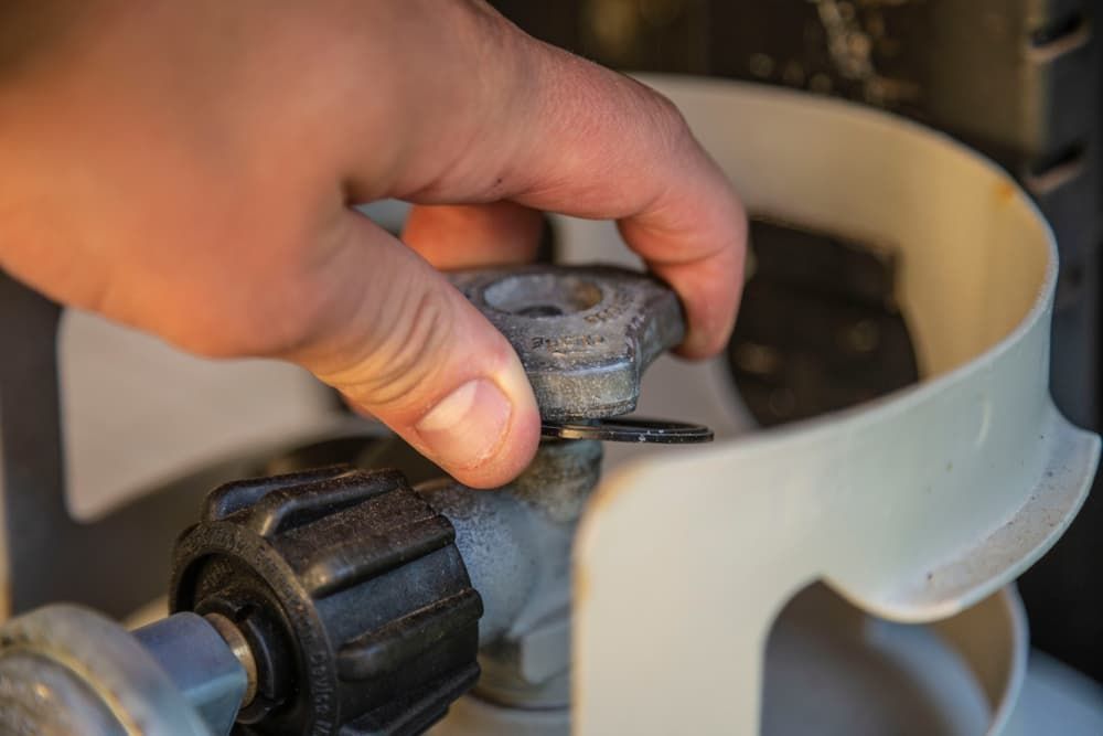 A Person is Opening a Valve on a Propane Tank — Mainline Plumbing & Civil Pty Ltd In Bourke, NSW