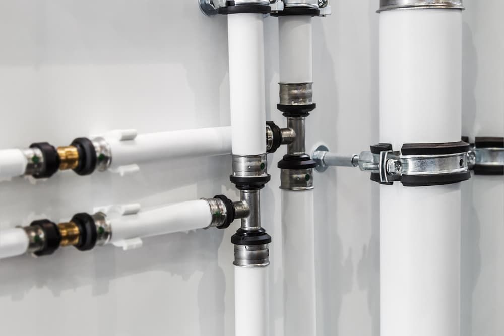 A Close Up of a Row of White Pipes Attached to a Wall — Mainline Plumbing & Civil Pty Ltd In Dubbo, NSW