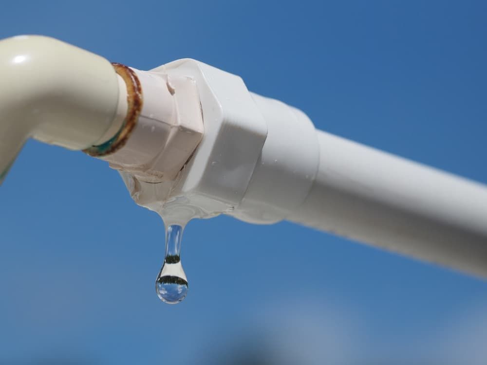 A White Pipe With a Drop of Water Coming Out of It — Mainline Plumbing & Civil Pty Ltd In Homebush, NSW