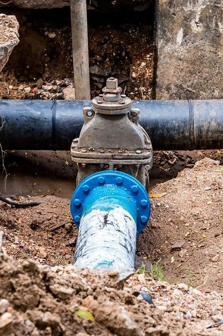 A Black Pipe With a Blue Flange is Sitting in the Dirt — Mainline Plumbing & Civil Pty Ltd In Bathurst, NSW