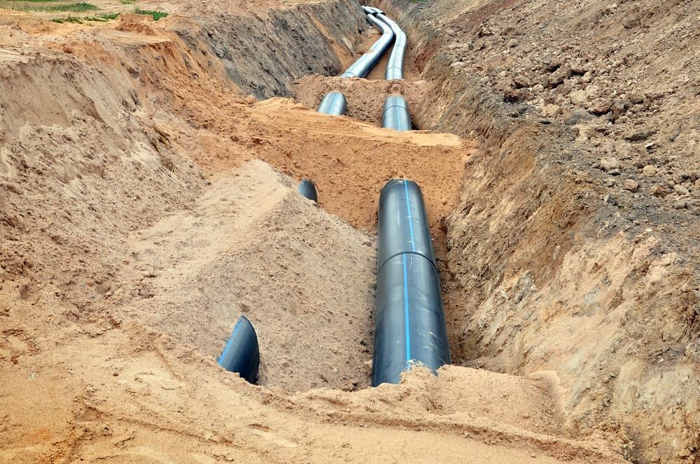 A Water Pipe is Being Installed in a Trench in the Dirt — Mainline Plumbing & Civil Pty Ltd in Dubbo, NSW