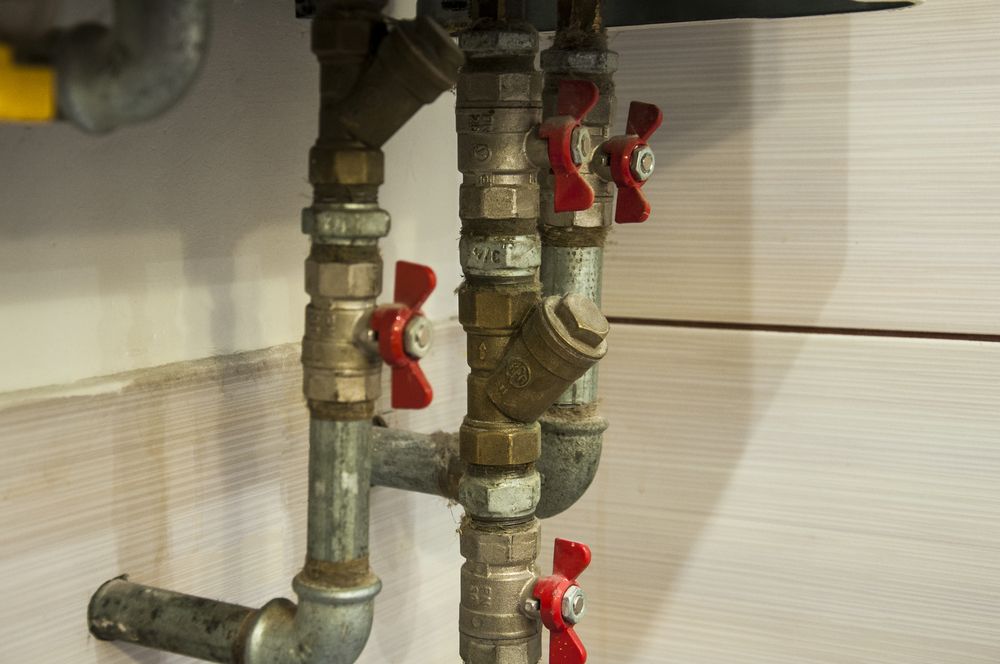 A Close Up of a Water Heater With Red Valves and Pipes — Mainline Plumbing & Civil Pty Ltd In Forbes, NSW