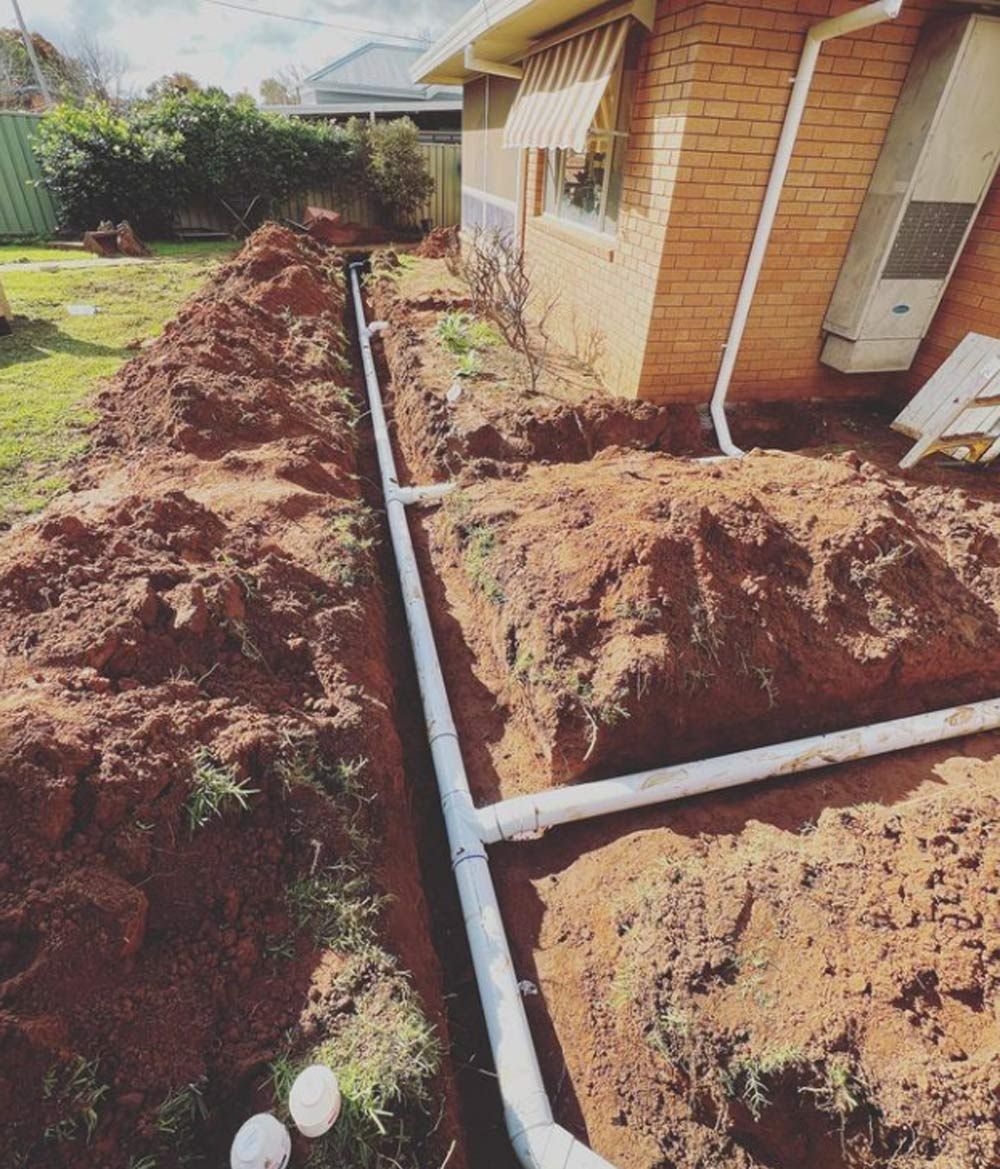 A Drainage System is Being Installed in Front of a Brick House — Mainline Plumbing & Civil Pty Ltd In Dubbo, NSW