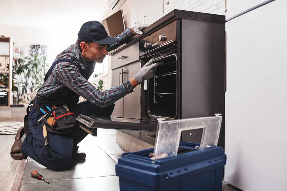 Worker Repairing An Oven — Mainline Plumbing & Civil Pty Ltd In Dubbo, NSW
