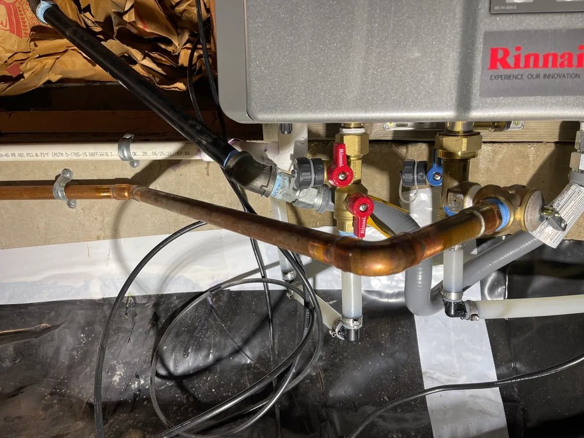 Rinnai water heater with copper pipes, valves, and black cables in a utility area