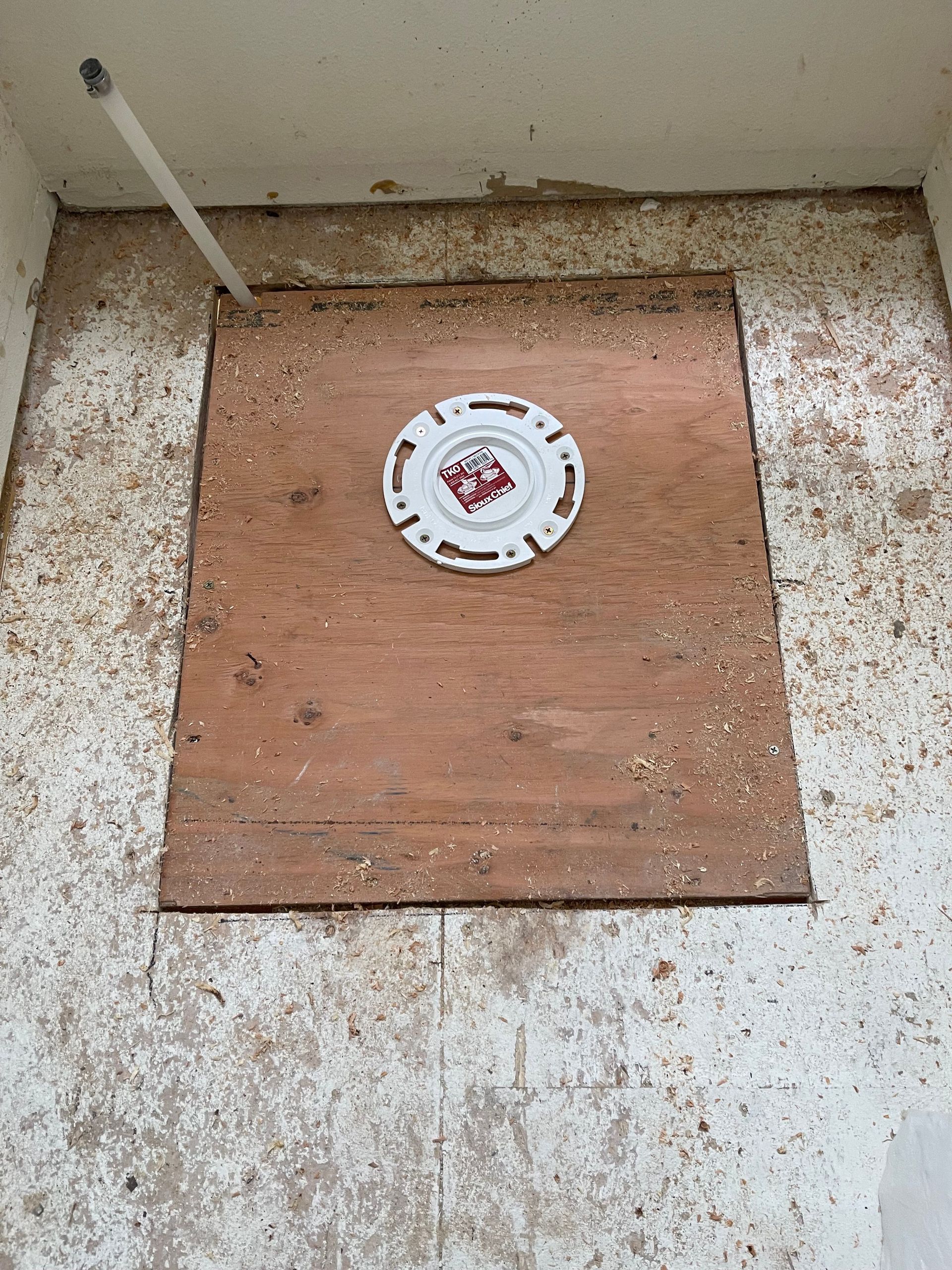 Square wooden panel with a round white cap in a dirty indoor utility corner