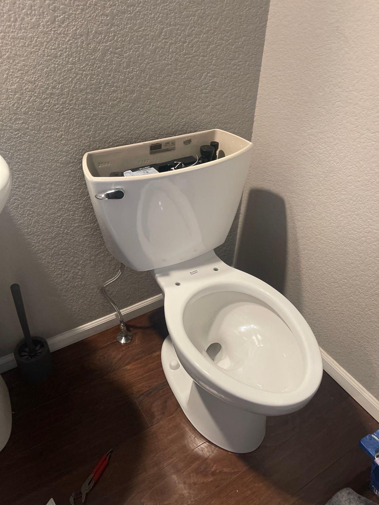 Damaged white toilet with tank lid off in a small bathroom corner