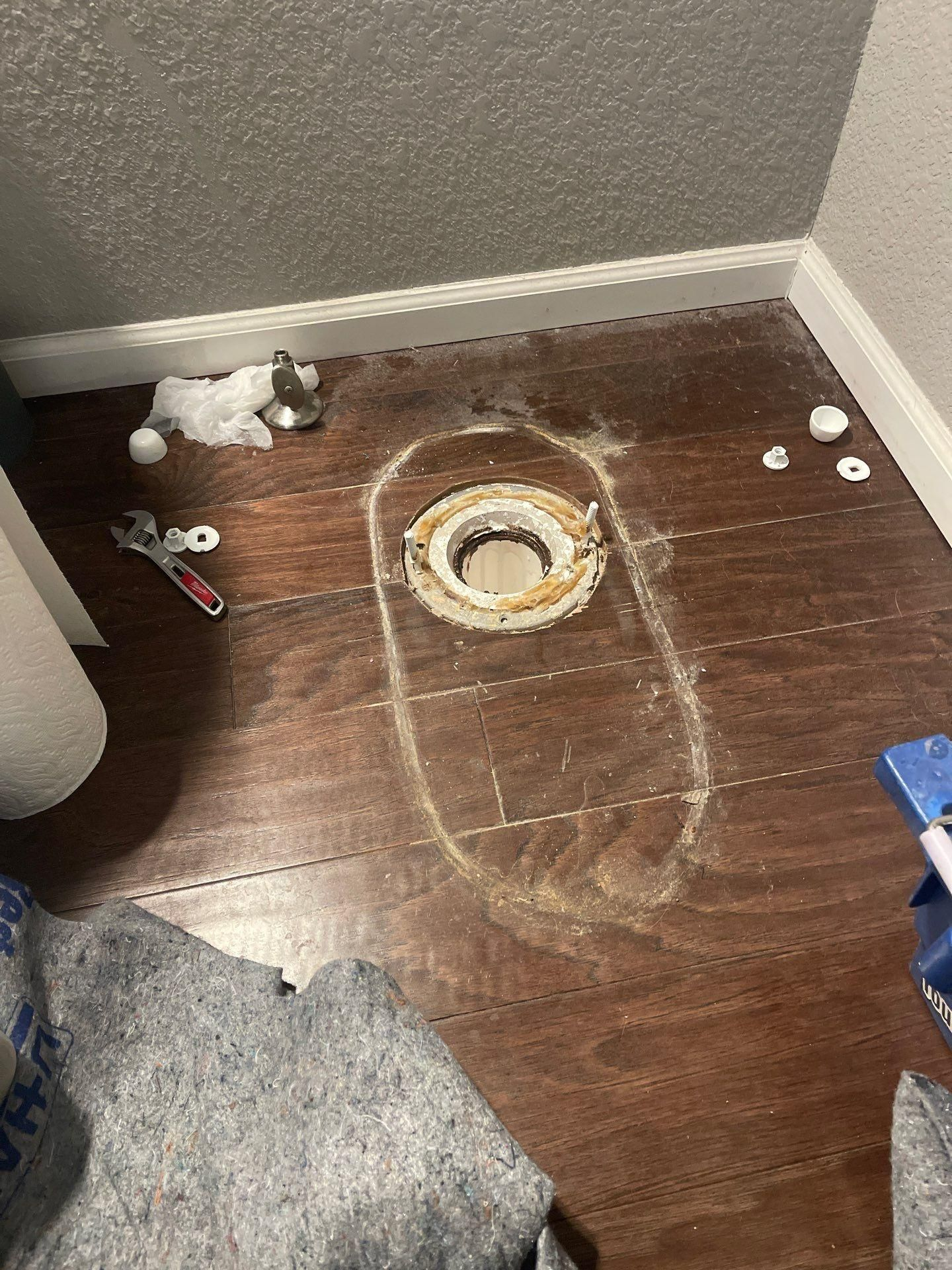 Bathroom floor with exposed toilet drain, chalk outline, and cleaning supplies nearby