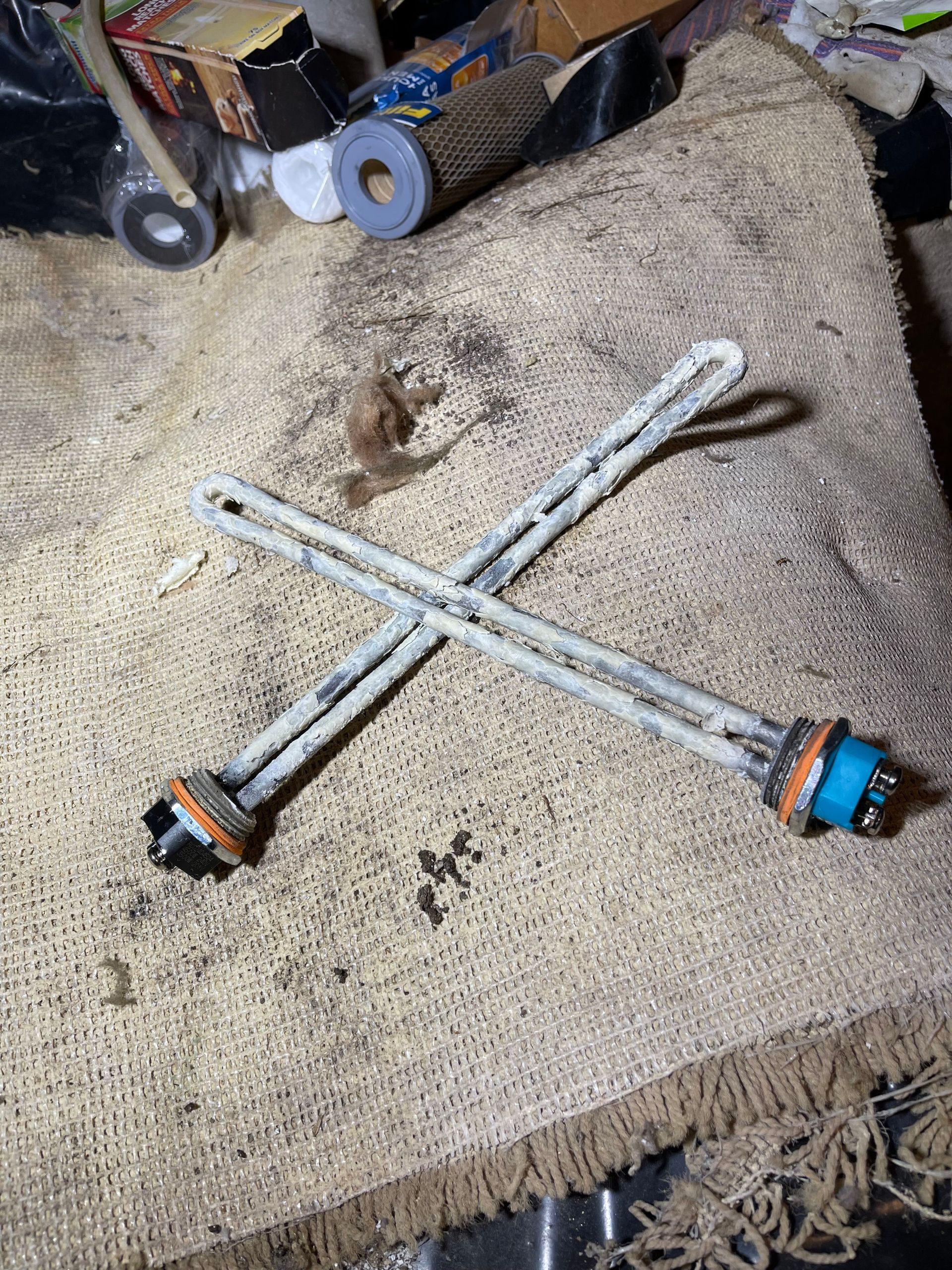 Two crossed metal rods with blue and orange ends lying on a beige carpet.