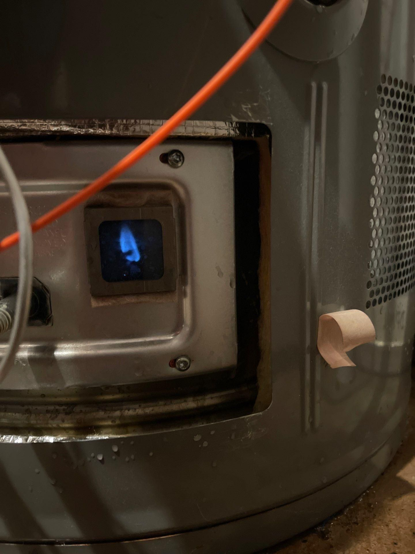 Close-up of a black appliance with a small blue-lit display and an orange cord across the front.