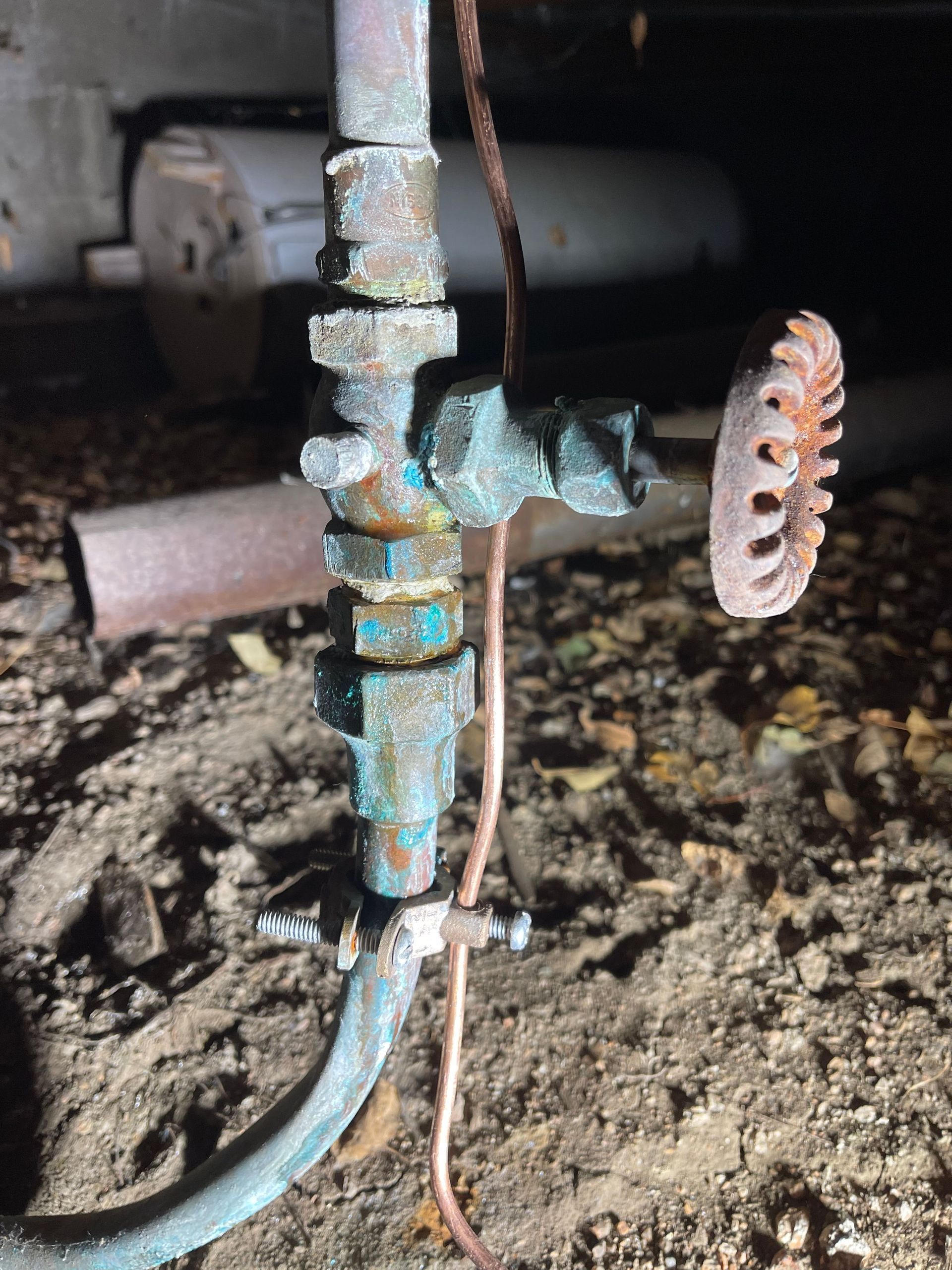 Corroded outdoor water valve with rusted metal pipes and a blue hose connected to it