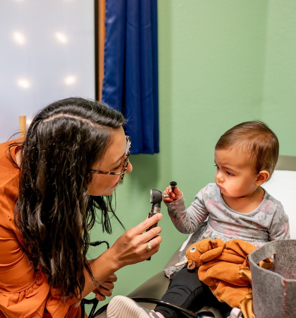 A woman nurse is showing a flashlight tool to a baby