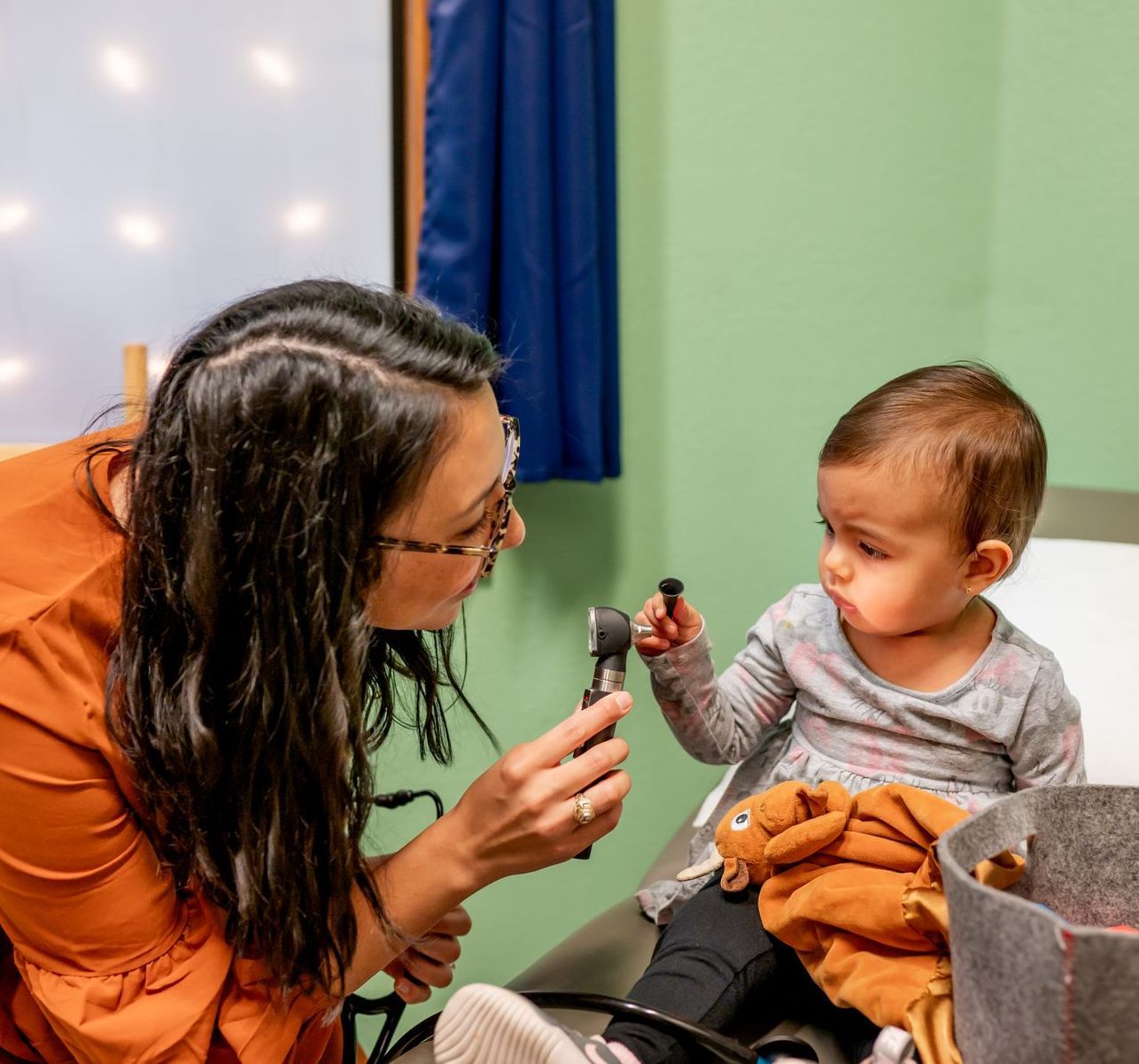 A woman nurse is showing a flashlight tool to a baby