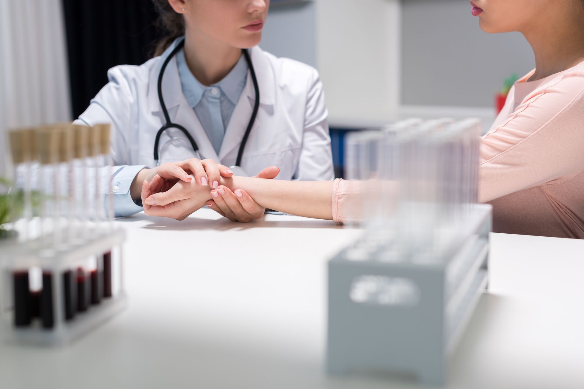 A doctor is holding the hand of a patient while taking her pulse.