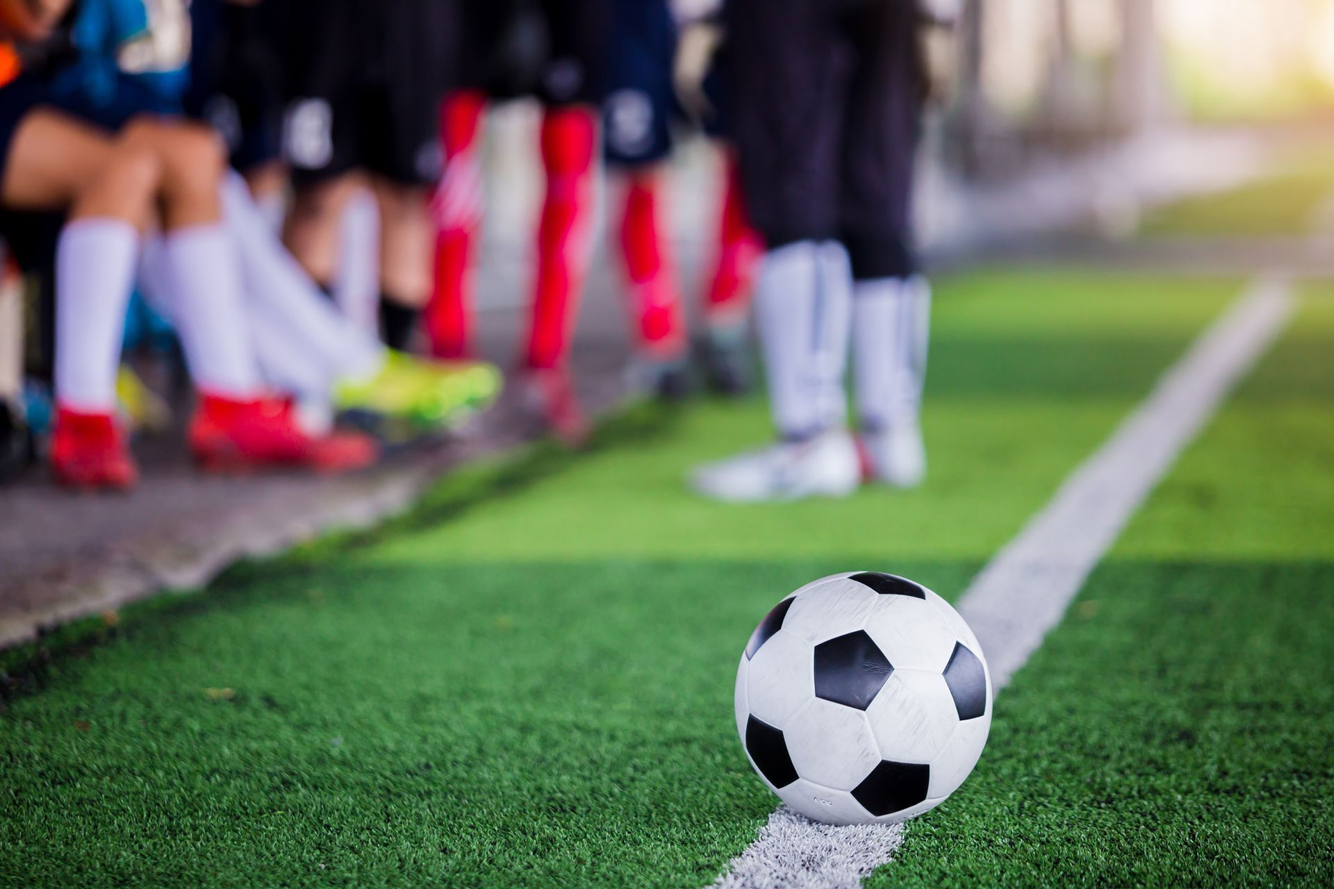 A soccer ball is on the line of a soccer field.