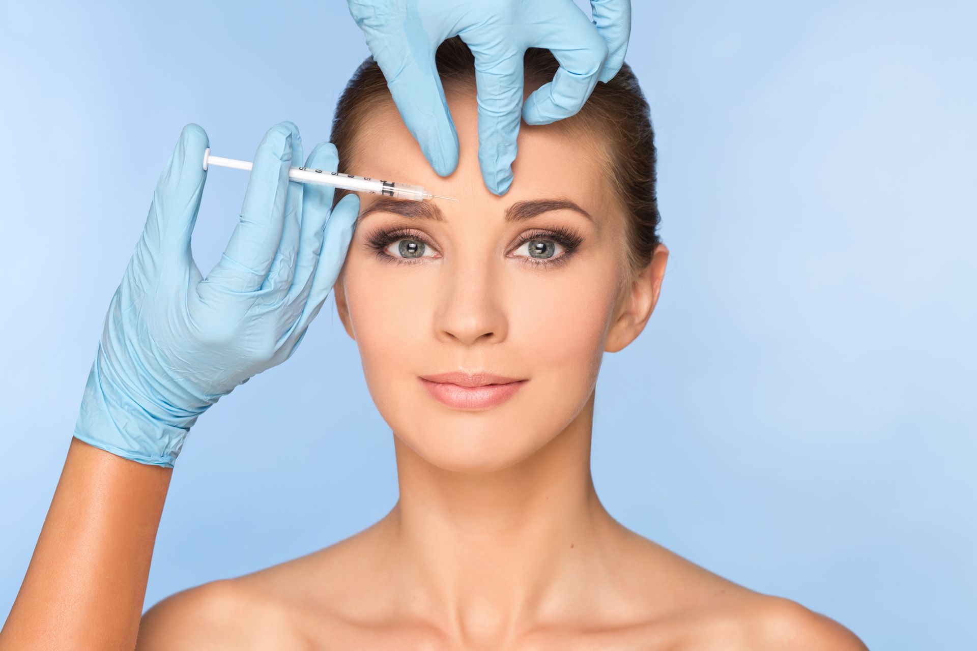 A woman is getting a botox injection in her forehead.