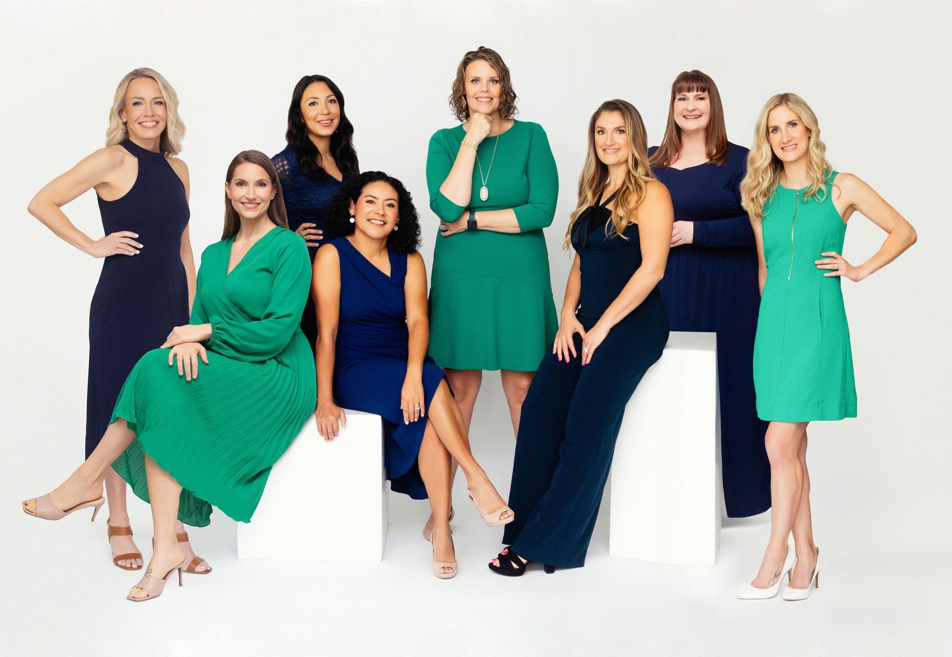 A group of women in blue and green dresses are posing for a picture.