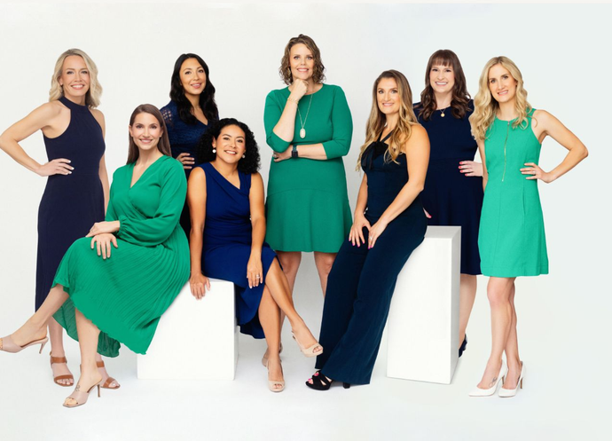 A group of women in blue and green dresses are posing for a picture.