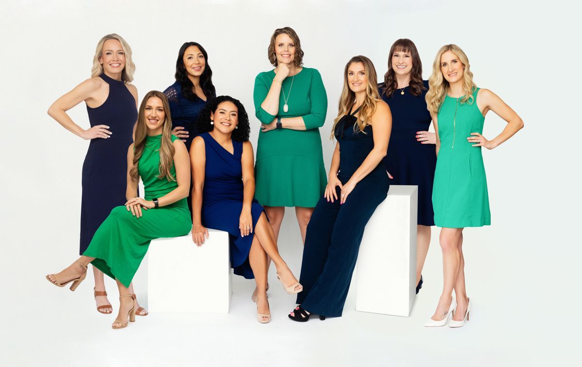 A group of women in blue and green dresses are posing for a picture.