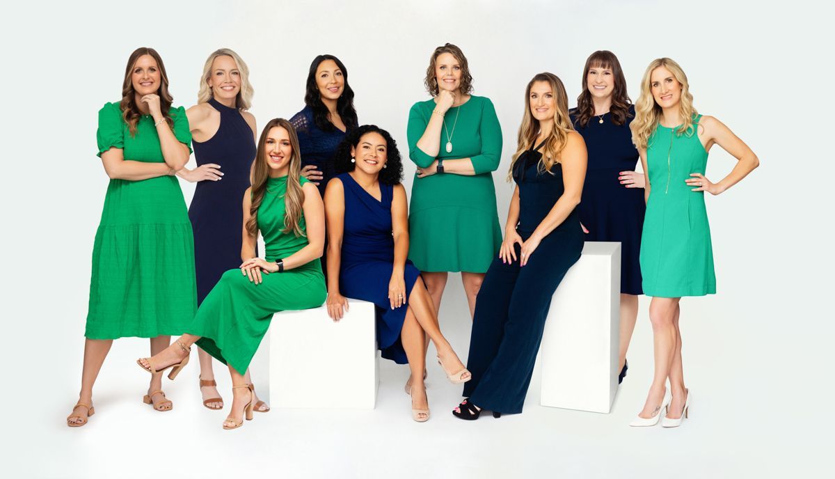A group of women in blue and green dresses are posing for a picture.