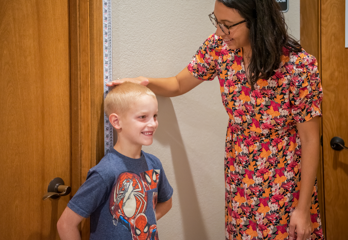 A woman is checking a young kid's height.