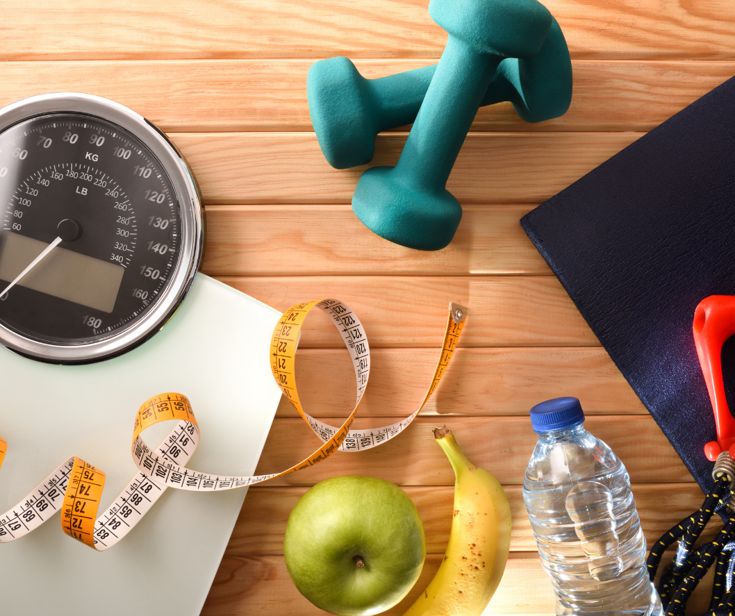 A collection of health and fitness essentials, including a scale, green dumbbells, measuring tape, w