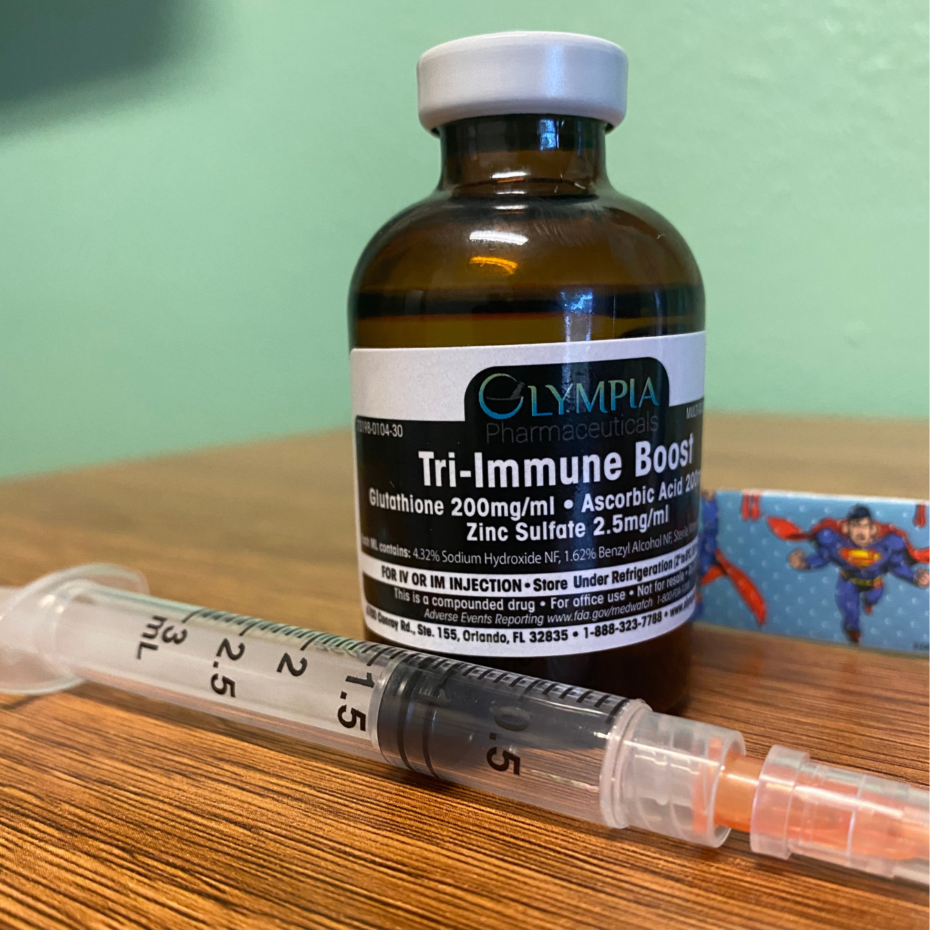 A syringe is sitting next to a bottle of tri-immune boost