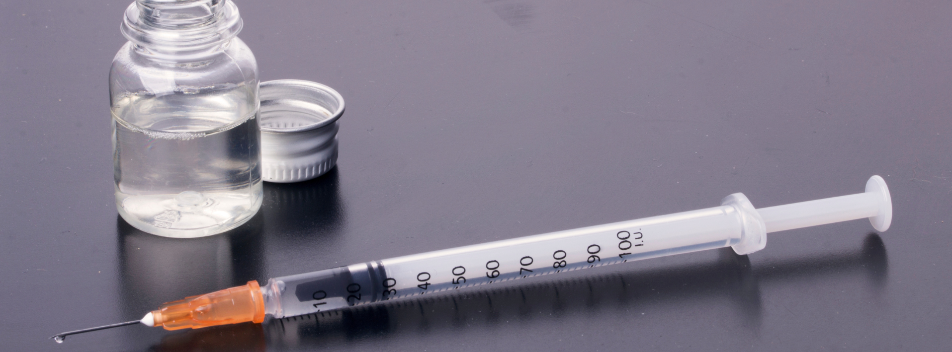 syringe beside a vial containing liquid