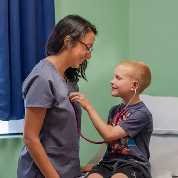 A woman is listening to a child 's heartbeat with a stethoscope.