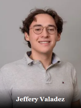 Young man with glasses smiling, wearing a gray polo shirt, against a gray background.