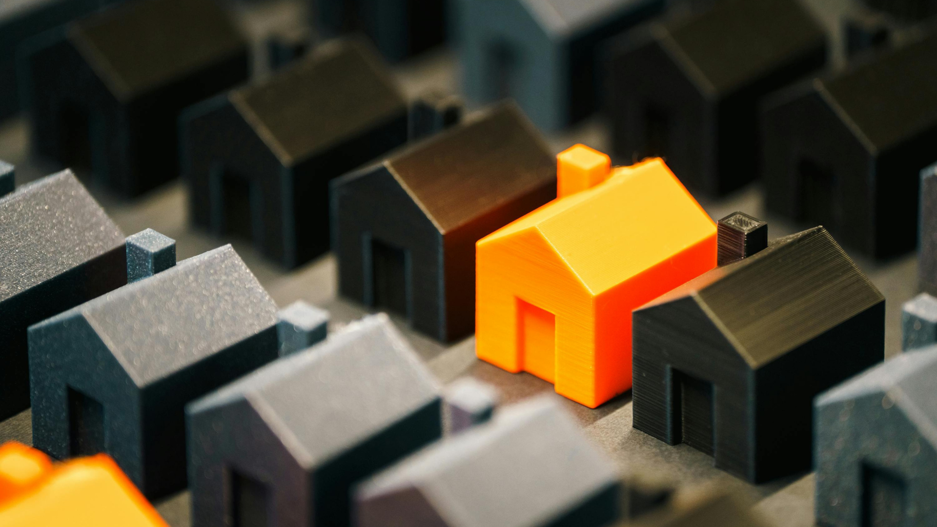 Orange house stands out among rows of gray and black miniature houses.