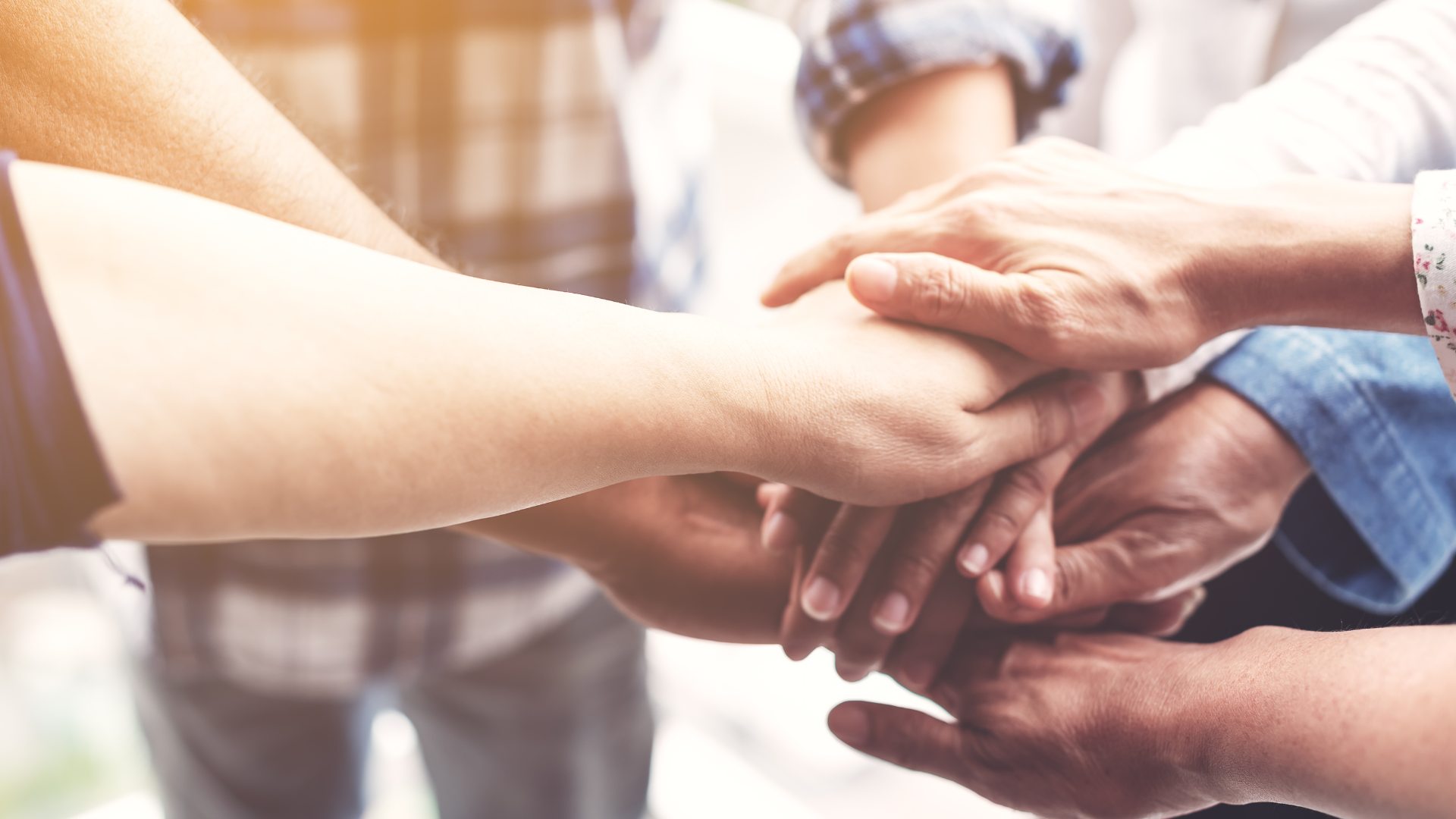 Hands of several people piled on top of each other, symbolizing teamwork.