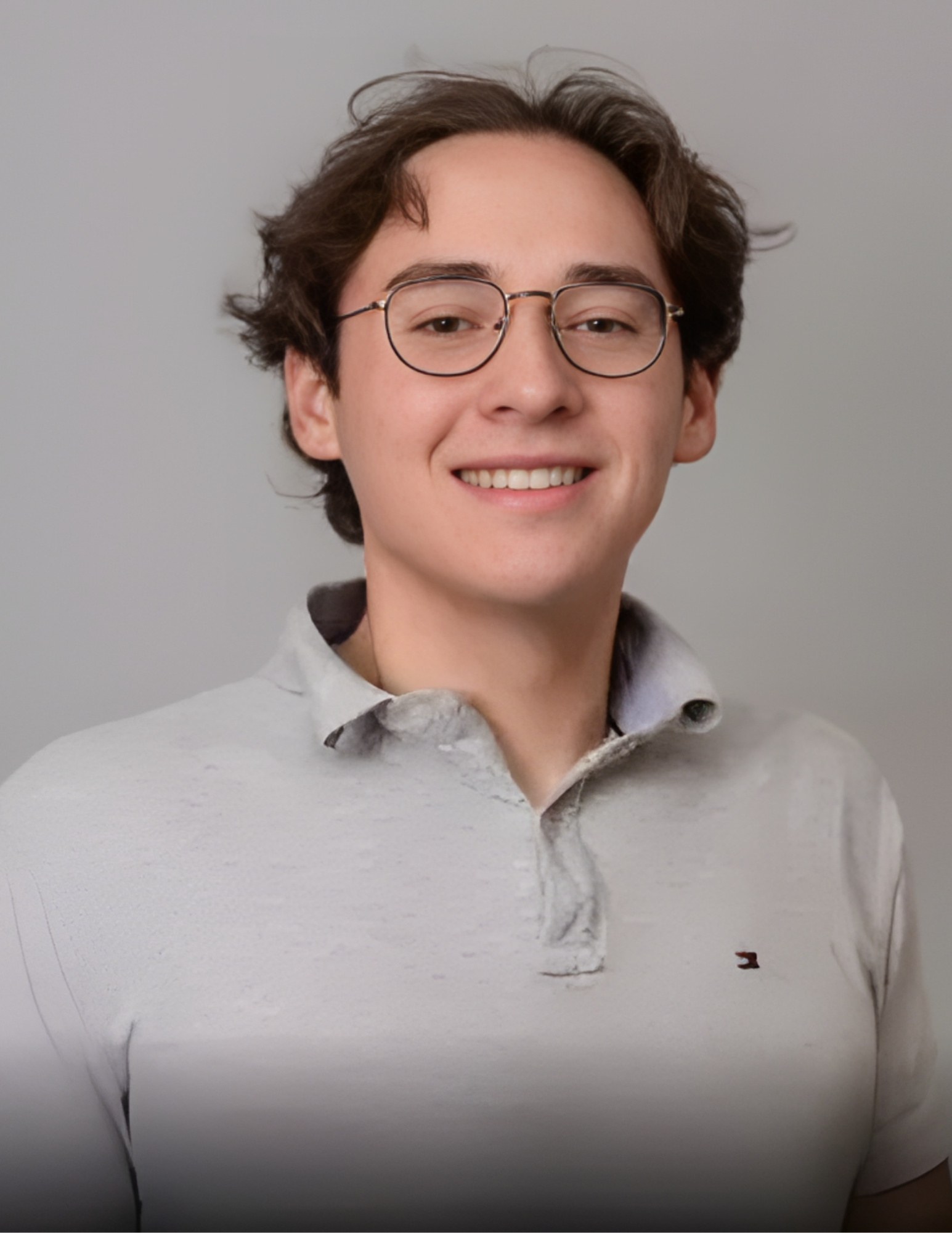 Smiling person wearing glasses and a gray polo shirt against a light gray background.