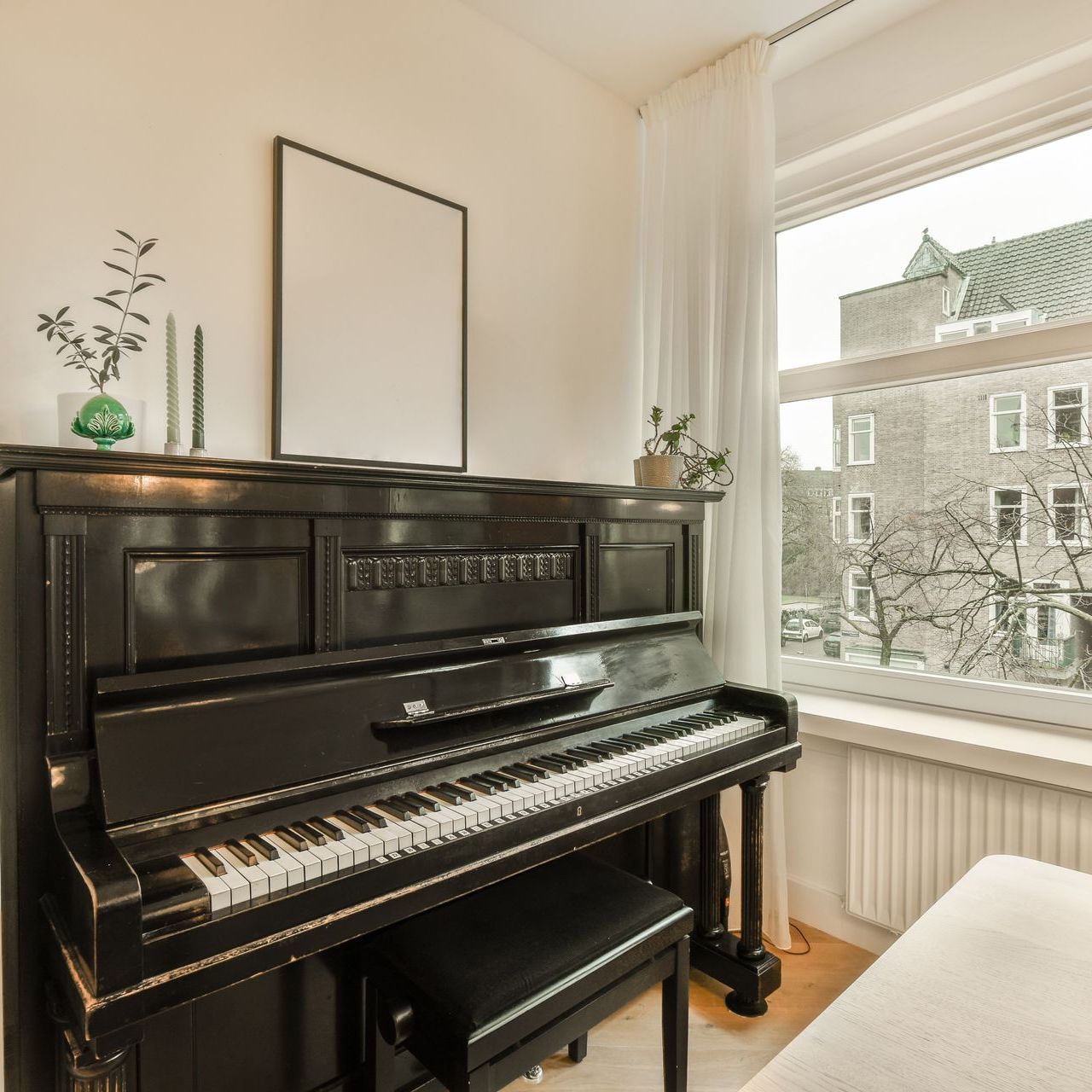 a black piano is sitting in a room next to a window