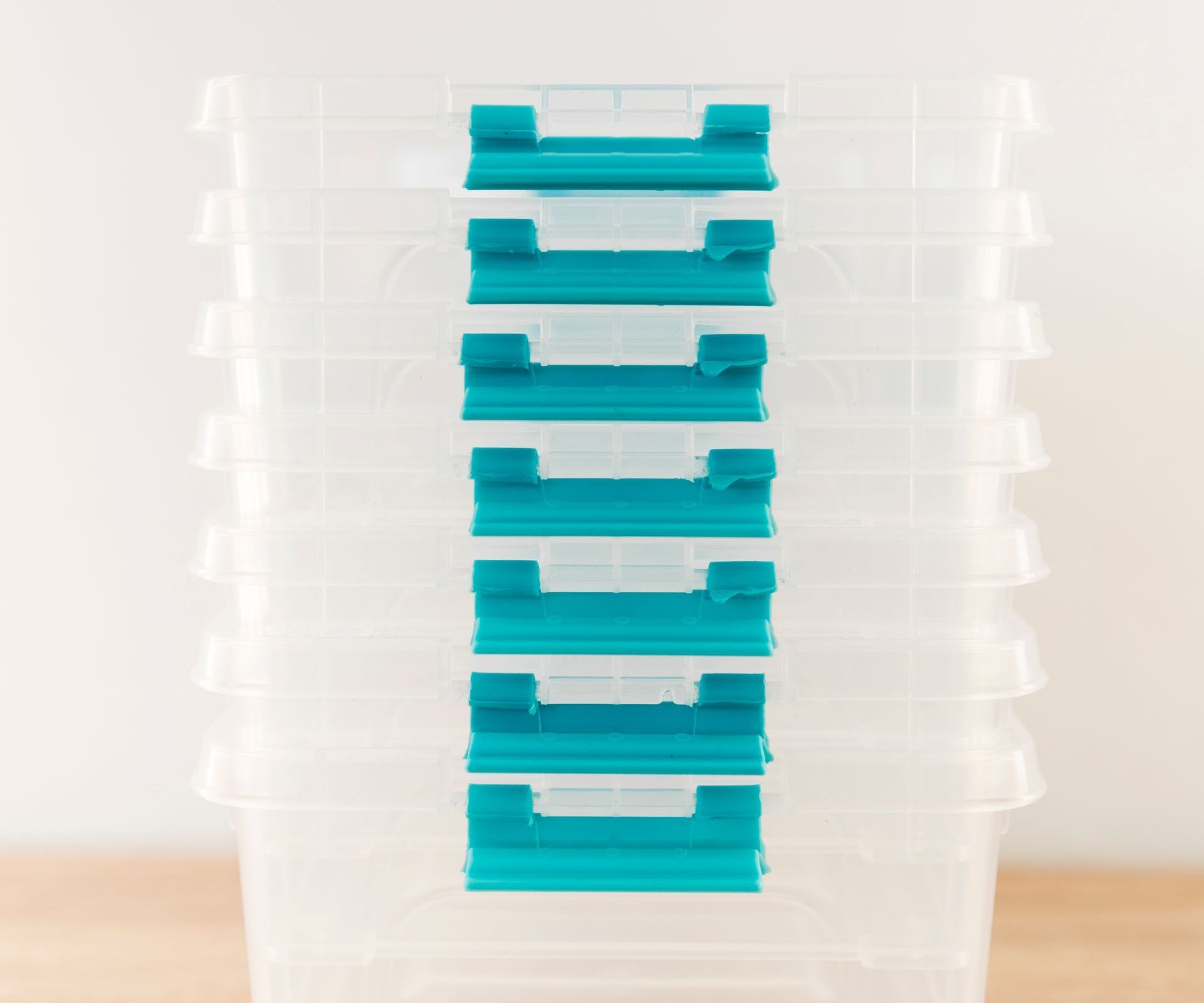 a stack of clear plastic containers with blue handles on a wooden table .
