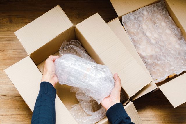 a person is packing a box with bubble wrap .