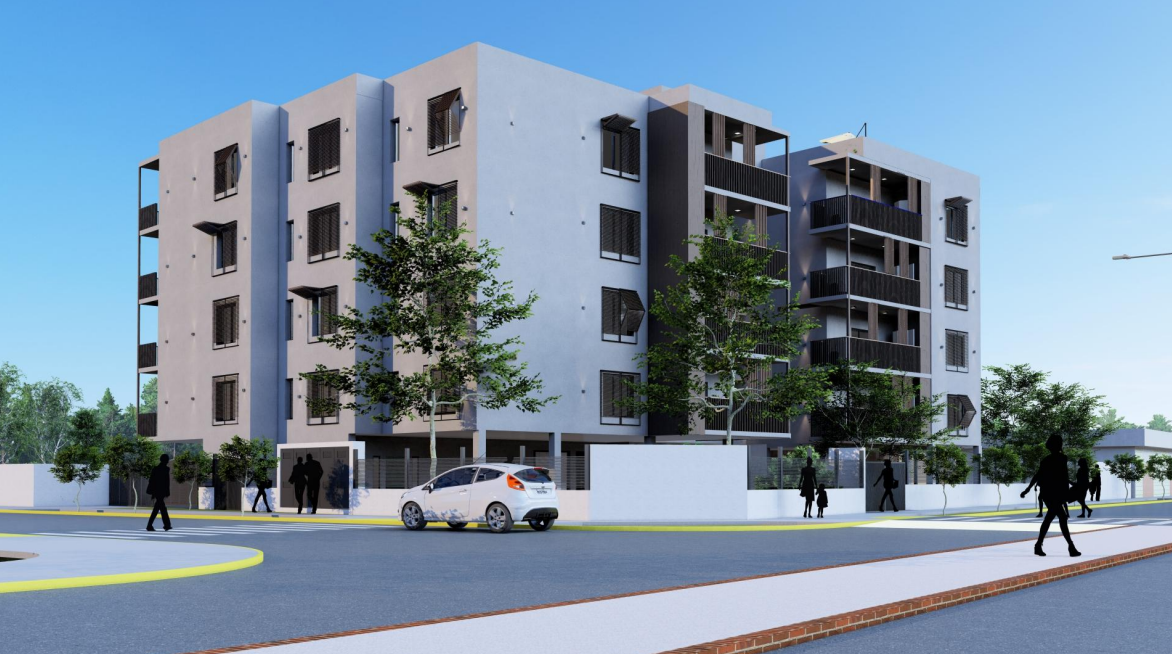 Edificio de apartamentos con fachada blanca y balcones oscuros; árboles, coches y peatones en una calle.