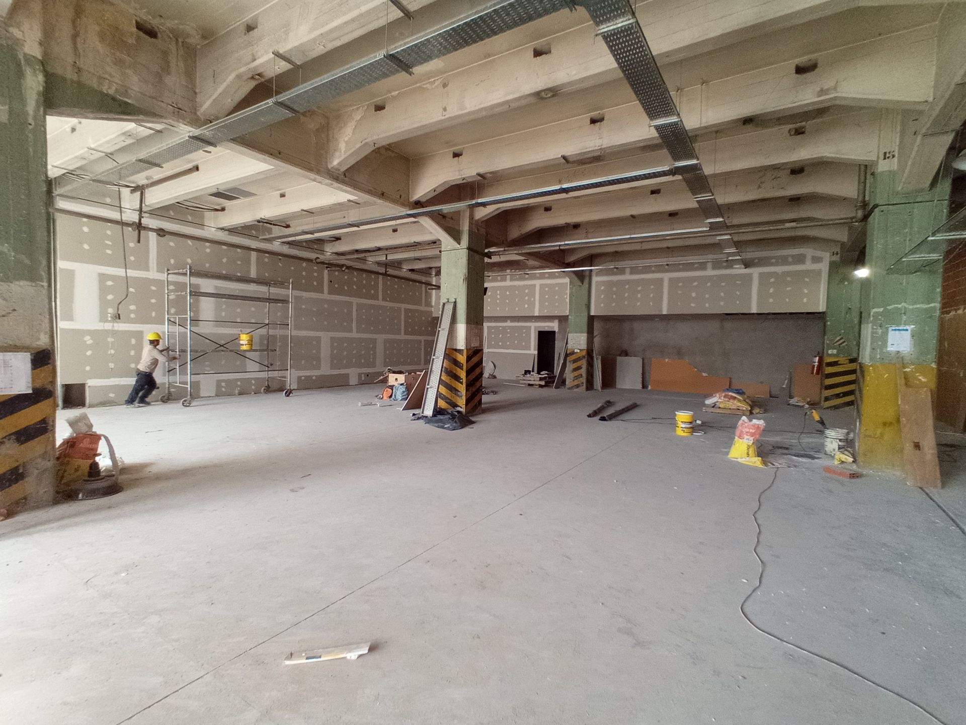 Interior de un edificio en construcción. Obreros, paneles de yeso, suelo de hormigón, vigas de soporte