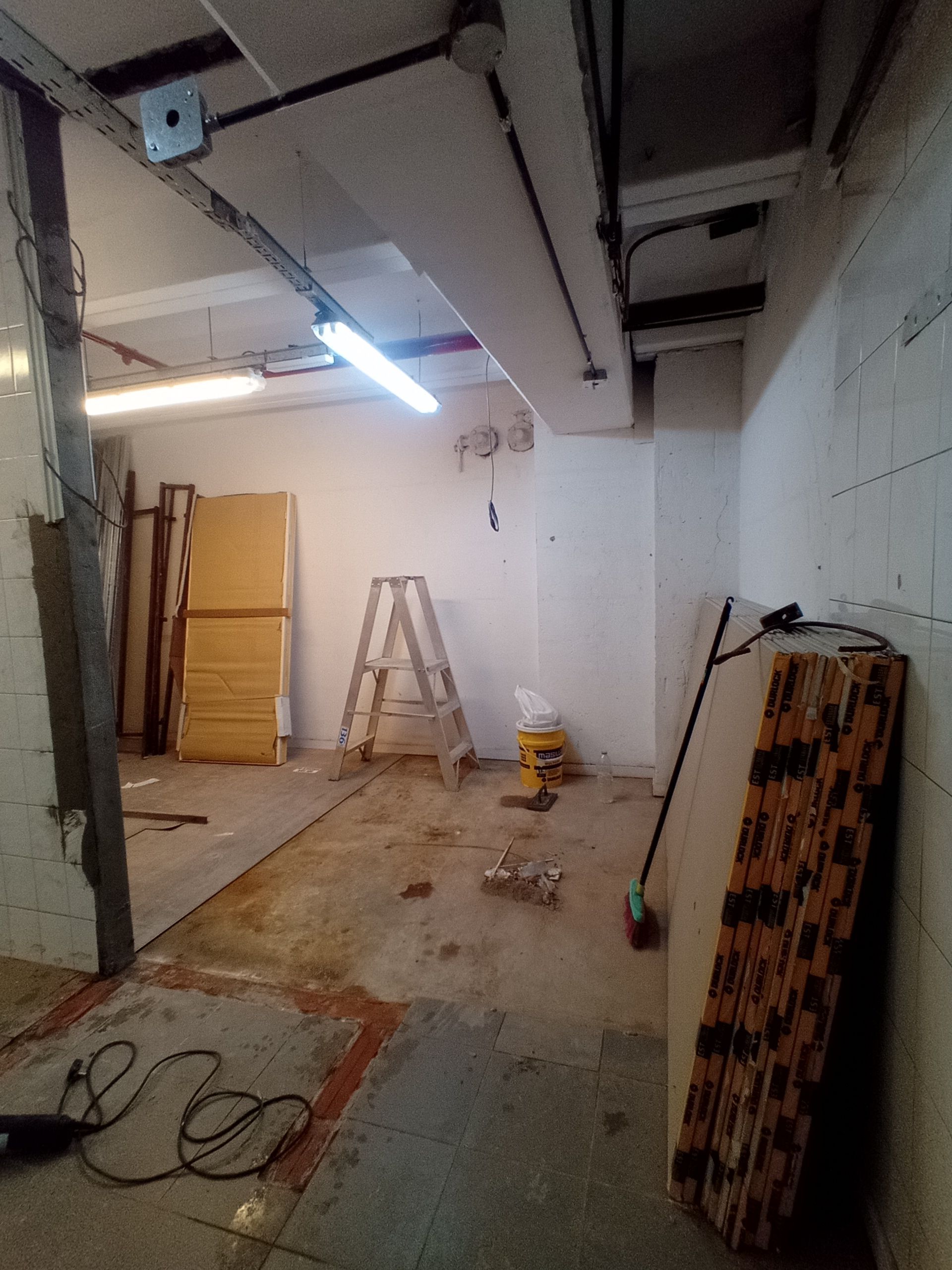 Toma interior de una habitación en construcción con cableado, herramientas y materiales de construcción expuestos.