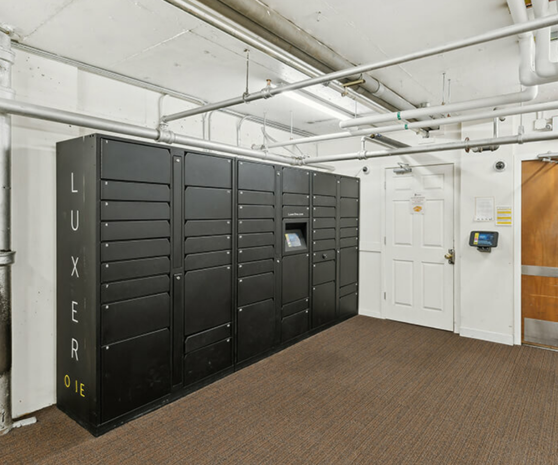 A room with a lot of black lockers and a door.
